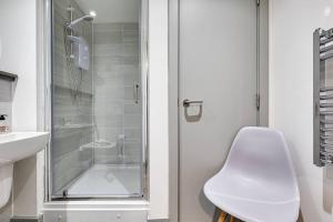 a white bathroom with a shower and a white chair at Modern & Centrally Located Apartment in Liverpool