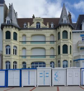 een groot geel gebouw met een bruin dak bij Au gré du vent in Wimereux