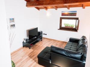 ein Wohnzimmer mit einem schwarzen Ledersofa und einem Flachbild-TV in der Unterkunft A Casa Mia B&B in Barisciano
