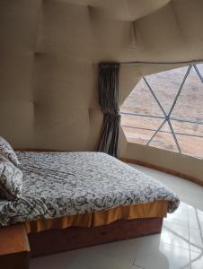 a bedroom with a bed in front of a window at Al Raha Luxury Camp in Wadi Rum