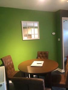 une table et des chaises dans une pièce dotée d'un mur vert dans l'établissement Greyfriar House, à Brumby