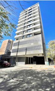 a tall building with a car parked in front of it at Departamentos y monoambientes Santiago 115 in Neuquén