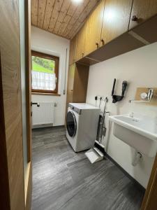 a bathroom with a washing machine and a sink at Stroblhof in Vipiteno