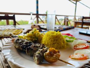 um prato de alimentos com carne e arroz numa mesa em Monte Mar SãoTomé em M. Peixe