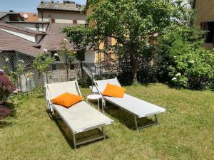 Dos sillas blancas con cojines naranjas en la hierba en Appartamento Poli con giardino, en Castiglione dei Pepoli