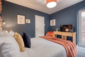 a bedroom with blue walls and a large bed at Malvern Hills Rosa Rambler Suite in Great Malvern