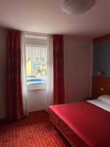 um quarto com uma cama vermelha e uma janela em Hotel Londra Slow Living Molveno em Molveno