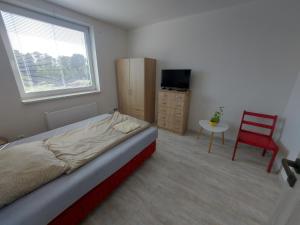 ein Schlafzimmer mit einem Bett und einem roten Stuhl in der Unterkunft Apartmán Rudoltice 