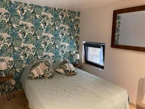 a bedroom with a bed with a green and white wallpaper at La Bergerie in Saint-Vincent
