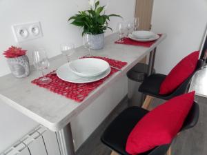 una mesa con sillas rojas, platos y copas de vino en Charmant appartement proche du centre ville, en Caen