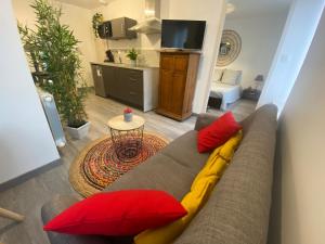 sala de estar con sofá y almohadas rojas y amarillas en Charmant appartement proche du centre ville, en Caen
