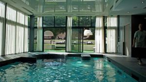 a large swimming pool in a building with glass doors at La maison des Sablons in Chartres