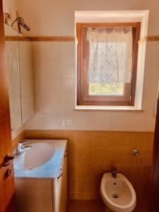 een badkamer met een wastafel, een toilet en een raam bij Casetta Gianni&Bea in Rocca di Cambio