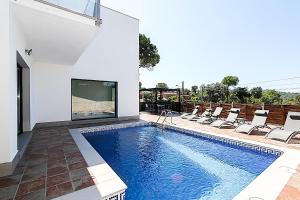 a swimming pool in a house with chairs and a fireplace at Villa Esperanza in Vidreres