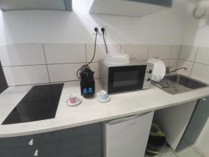 - une cuisine avec un four micro-ondes et 2 tasses sur un comptoir dans l'établissement Narbonne Domitia centre ville, à Narbonne