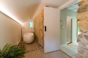 ein Badezimmer mit einer weißen Badewanne und einer Steinmauer in der Unterkunft Weaver's Cottage in Smarden + 32 Fotos