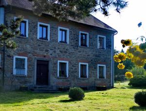 una antigua casa de ladrillo con ventanas blancas en un campo en Relax v Jizerkách, en Nové Město pod Smrkem