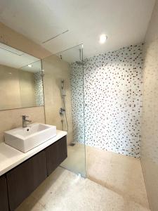 a bathroom with a sink and a glass shower at KL city 2 room in Regalia suites @ KLCC view infinity pool in Kuala Lumpur