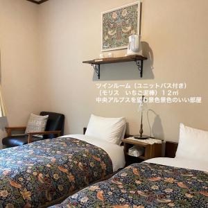 茅野市にあるゲストハウス クロイツェル 東急リゾートのベッド2台が備わる部屋、壁に絵が飾られた部屋