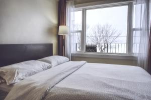 a bedroom with a large bed with a large window at Lakeside Inn in Orillia