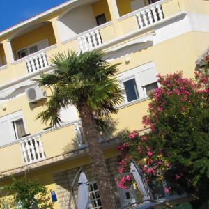 蘇科尚的住宿－倫賈克公寓，一座黄色的建筑,前面有棕榈树