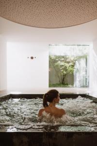a woman is sitting in a bath tub at Boutique-Hotel Ballguthof am Golfplatz in Lana