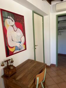 Habitación con una mesa de madera y una pintura en la pared. en Chez Madame, en Ferrara