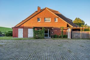 una casa arancione con un vialetto di mattoni davanti di Günthers Wattstube a Schweiburg