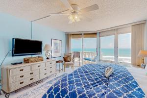 a bedroom with a bed and a television and the ocean at The Sea Goose in Ormond Beach
