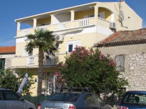 a yellow building with cars parked in front of it at Apartments Renjak in Sukošan