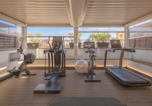 einen Fitnessraum mit Kardiogeräten in einem Zimmer mit Fenster in der Unterkunft The First Arte - Preferred Hotels & Resorts in Rom