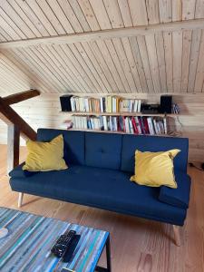 a blue couch with two yellow pillows in a room at Mon refuge en Vasgovie in Meisenthal