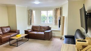 sala de estar con muebles de cuero marrón y ventana en Budget 2 Bedroom Apartment in Paddington, en Londres