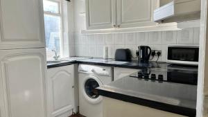 cocina blanca con lavadora y microondas en Budget 2 Bedroom Apartment in Paddington, en Londres