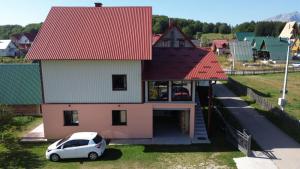 une petite voiture blanche garée devant une maison dans l'établissement Deluxe Studio & Rooms Zarubica, à Žabljak