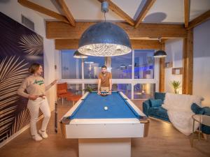 a man and woman standing in a living room with a pool table at Côté Thalasso Hôtel & Spa Marin in Banyuls-sur-Mer