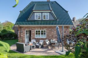 a brick house with a patio with chairs and an umbrella at Haus Traumzeit in Braderup