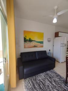 ein Wohnzimmer mit einem schwarzen Sofa und einem Kühlschrank in der Unterkunft Sweet Room Coroa Vermelha in Santa Cruz Cabrália