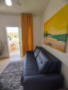 ein Wohnzimmer mit einem schwarzen Sofa und einem Gemälde in der Unterkunft Sweet Room Coroa Vermelha in Santa Cruz Cabrália