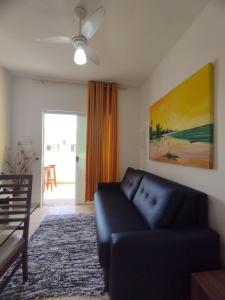 ein Wohnzimmer mit einem schwarzen Sofa und einem Gemälde in der Unterkunft Sweet Room Coroa Vermelha in Santa Cruz Cabrália