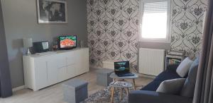 un salon avec un canapé bleu et une télévision dans l'établissement Au jardin de la seiche, à Noyal-Châtillon-sur-Seich