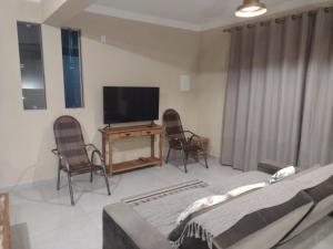 sala de estar con TV y 2 sillas en Vila Germânia, Casa Berlim en Pirenópolis