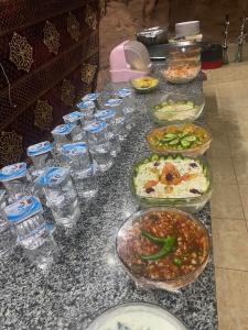 stół z miskami jedzenia i szklankami wody w obiekcie Wadi rum secrets camp w mieście Wadi Rum