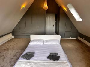 ein Schlafzimmer mit einem weißen Bett mit zwei schwarzen Schuhen darauf in der Unterkunft Large Family Home with great access to M2 & London in Wainscot