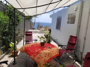 un patio con mesa, sillas y sombrilla en ptit coin hibiscus en Pointe-Noire