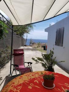 einen Tisch und einen Stuhl auf einer Terrasse mit einem Tisch in der Unterkunft ptit coin hibiscus in Pointe-Noire