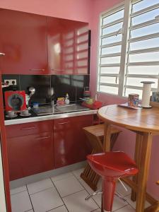 uma cozinha com armários vermelhos e uma mesa de madeira em ptit coin hibiscus em Pointe-Noire
