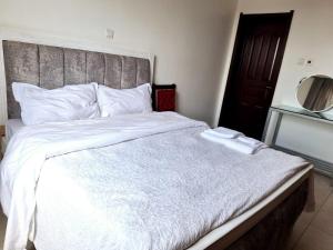 sypialnia z dużym białym łóżkiem z drewnianym zagłówkiem w obiekcie Jkia 3 bedroom greatwall gardens phase 4 w mieście Athi River