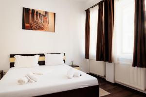 - une chambre dotée d'un lit avec des draps blancs dans l'établissement Old City, à Bucarest
