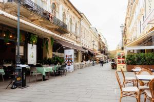 eine leere Straße mit Tischen, Stühlen und Gebäuden in der Unterkunft Old City in Bukarest